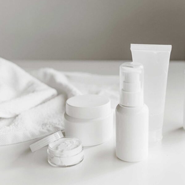 This photograph features a towel and a set of skincare products. Minimalist skincare involves using a few products that benefit skin.