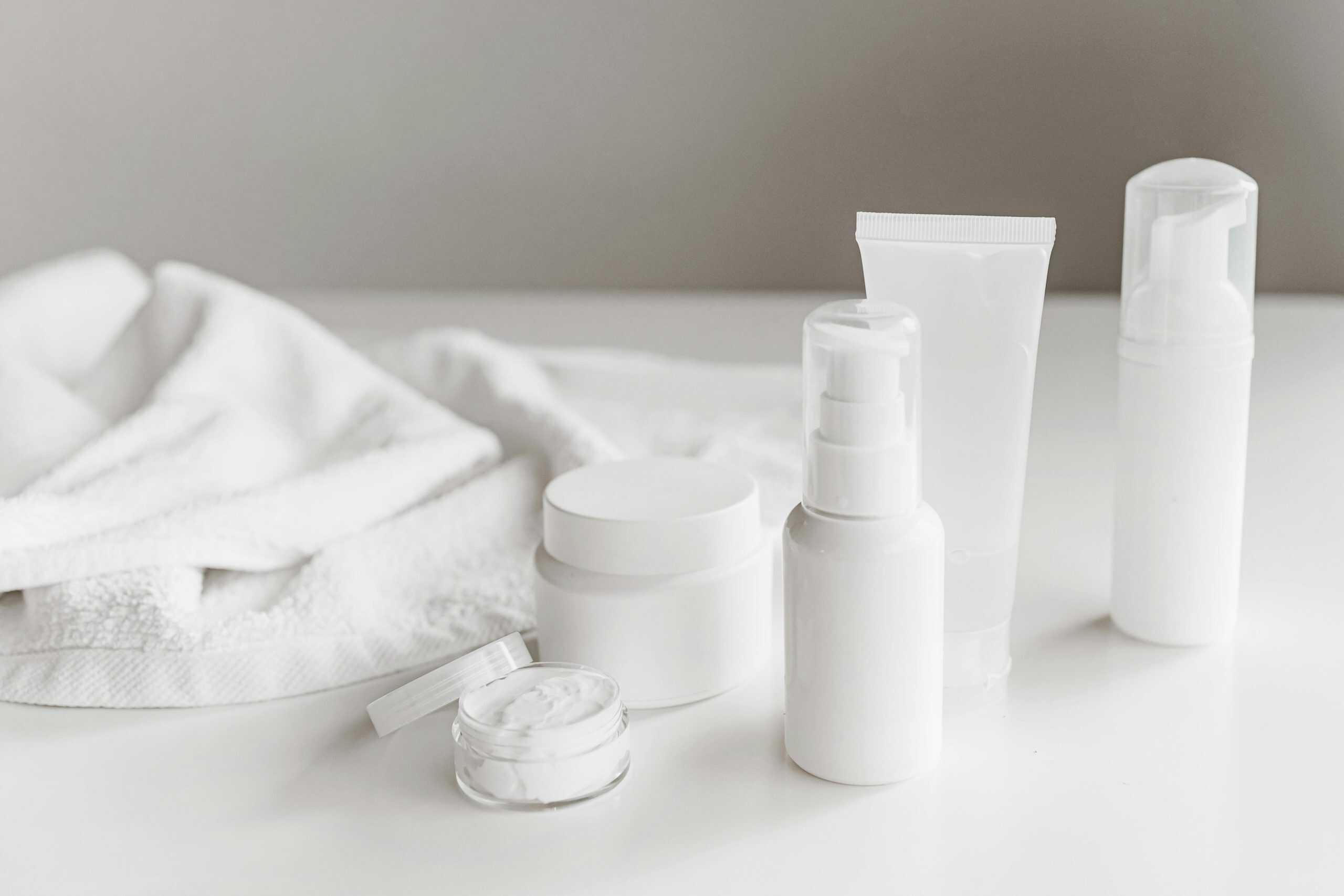 This photograph features a towel and a set of skincare products. Minimalist skincare involves using a few products that benefit skin.