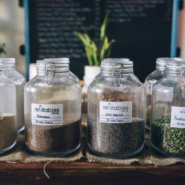 Glass jars in a store containing organic seeds like quinoa and flax, promoting sustainable living. chia seeds flax seeds