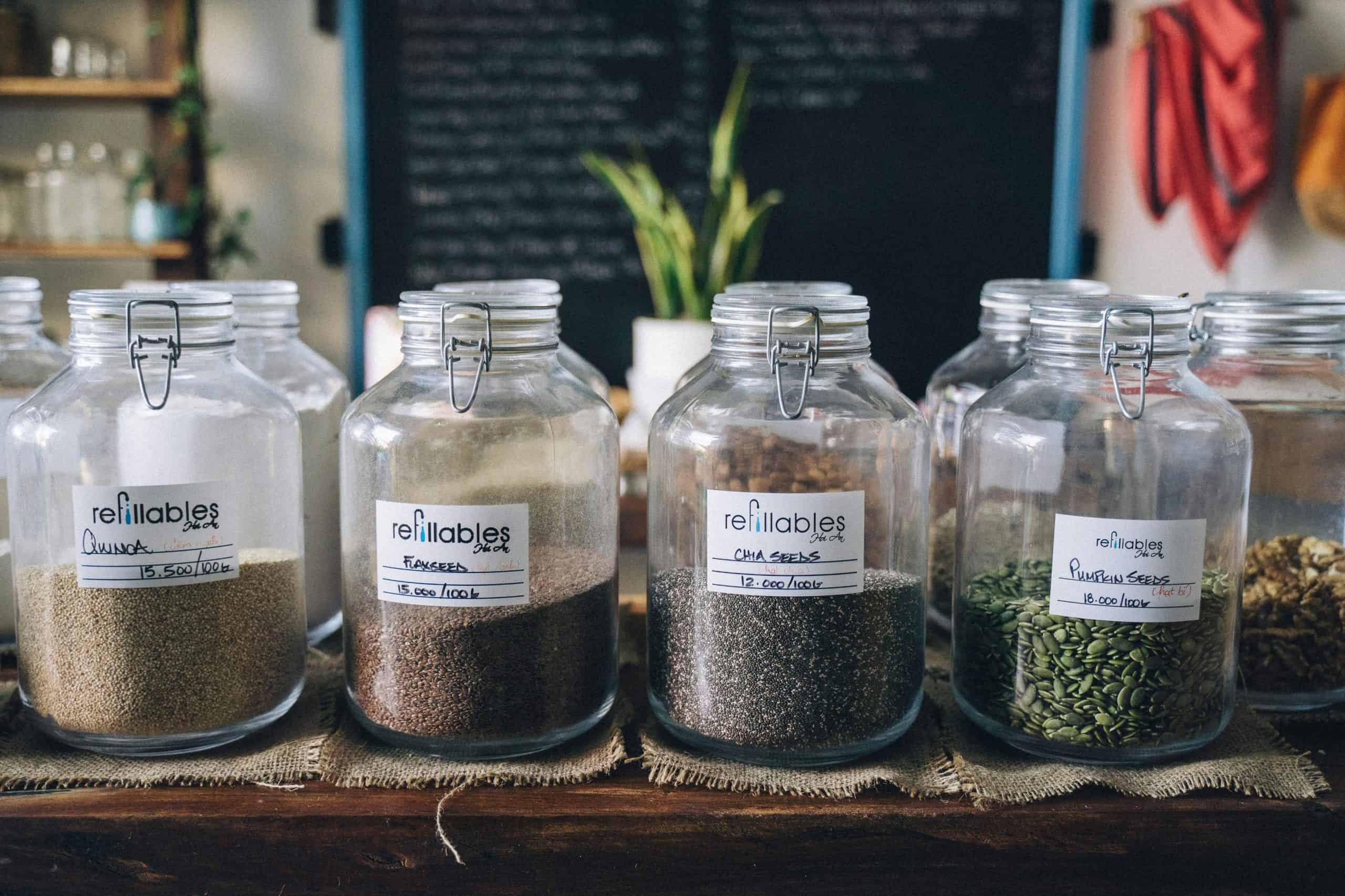 Glass jars in a store containing organic seeds like quinoa and flax, promoting sustainable living. chia seeds flax seeds