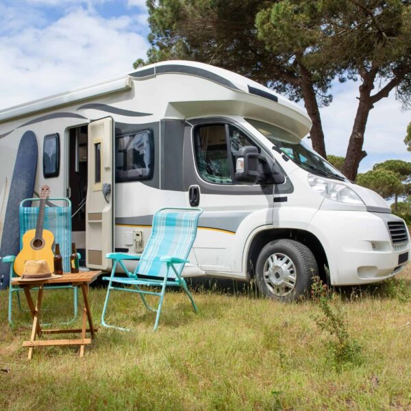Explore the outdoor lifestyle with an RV, surfboards, and guitar in a serene Portuguese park. RV Parks