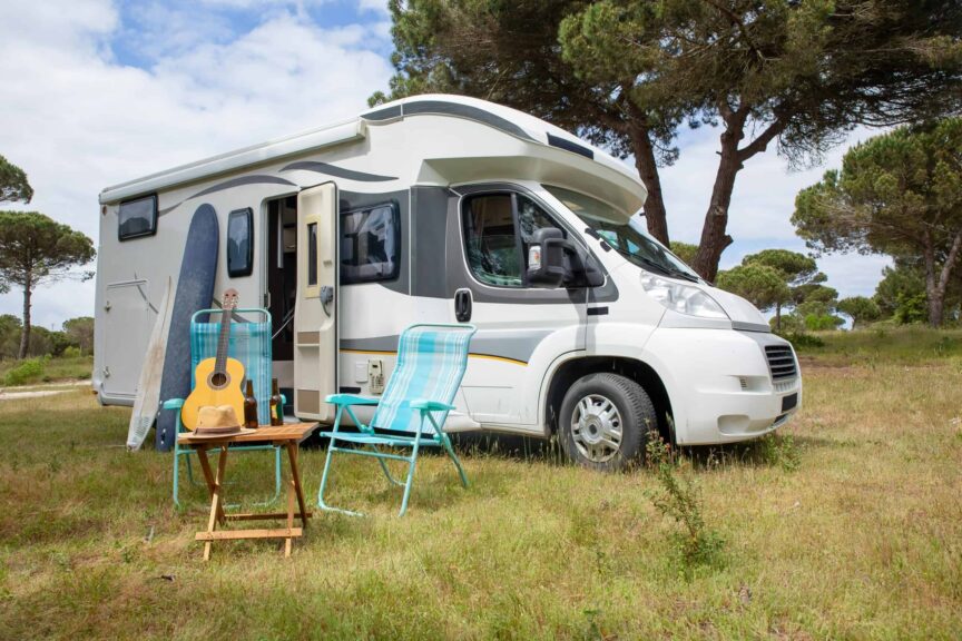 Explore the outdoor lifestyle with an RV, surfboards, and guitar in a serene Portuguese park. RV Parks
