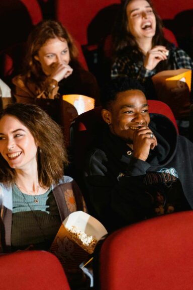 Friends share popcorn in a movie theater, the kind of big-screen outing Netflix plans for KPop Demon Hunters 2