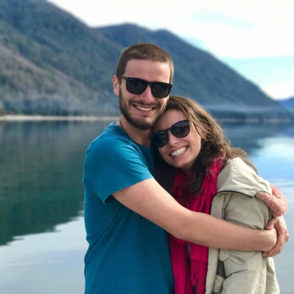 This photograph features a happy couple smiling in front of a lake. Going someplace new together can help you renew passion in your relationship.