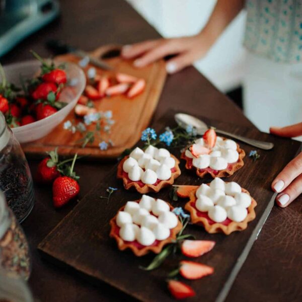Freshly prepared strawberry tarts with cream on a wooden board, perfect for a delightful dessert., Labor Day