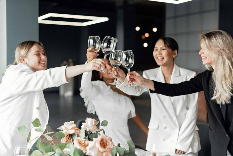 Two women celebrating long-distance friendships indoors, clinking wine glasses with joyful smiles during a toast. Photo by Mikhail Nilov via Pexels.