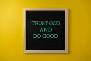 Inspirational message 'Trust God and Do Good' on a stylish black letter board with a vibrant yellow background. Proverbs 3