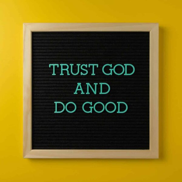 Inspirational message 'Trust God and Do Good' on a stylish black letter board with a vibrant yellow background. Proverbs 3