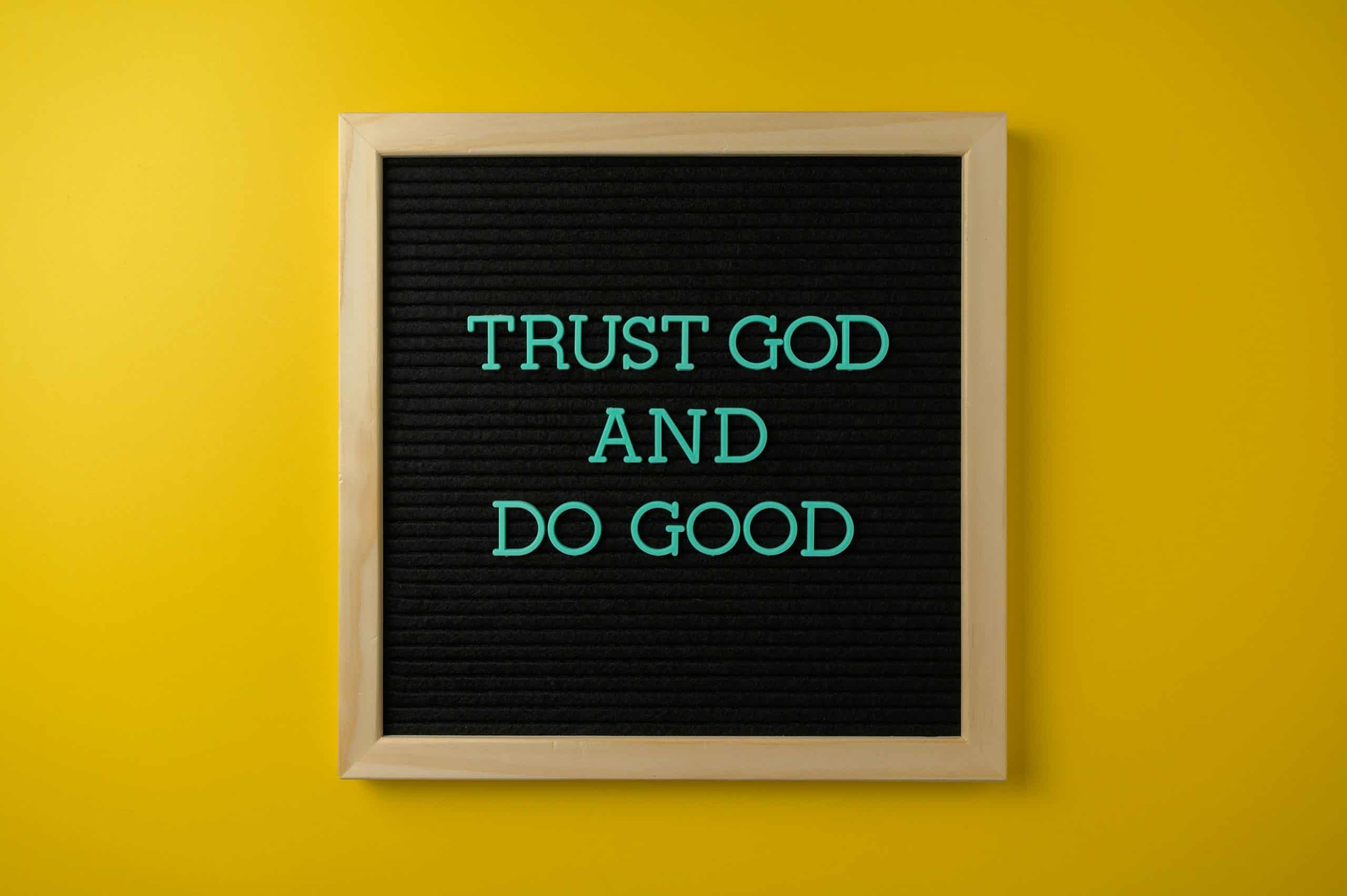 Inspirational message 'Trust God and Do Good' on a stylish black letter board with a vibrant yellow background. Proverbs 3