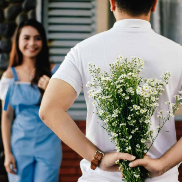 A man surprises his partner with flowers behind his back, symbolizing love and romance. dating, faith