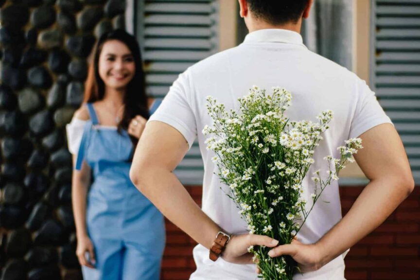 A man surprises his partner with flowers behind his back, symbolizing love and romance. dating, faith