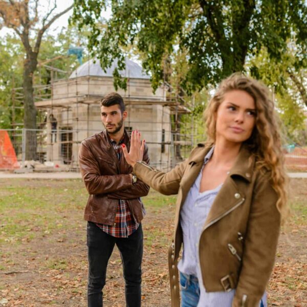 A couple faces disagreement outdoors in a park setting showcasing emotional expressions.
