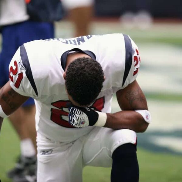 NFL Preseason, Football player in uniform kneeling before a game, displaying focus and determination.