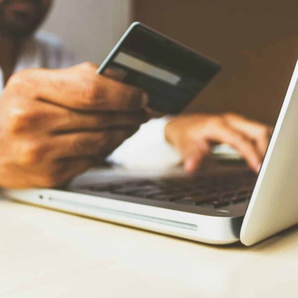 A person using a laptop and holding a credit card. , travel scams