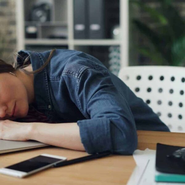 A woman laying her head on a laptop on a desk. Hashimoto's disease