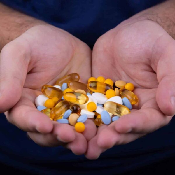 A person holding a handful of pills / vitamin patch
