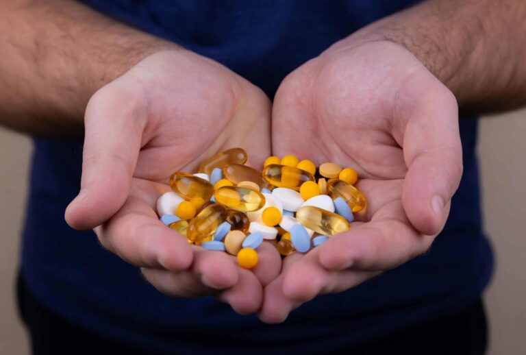 A person holding a handful of pills / vitamin patch