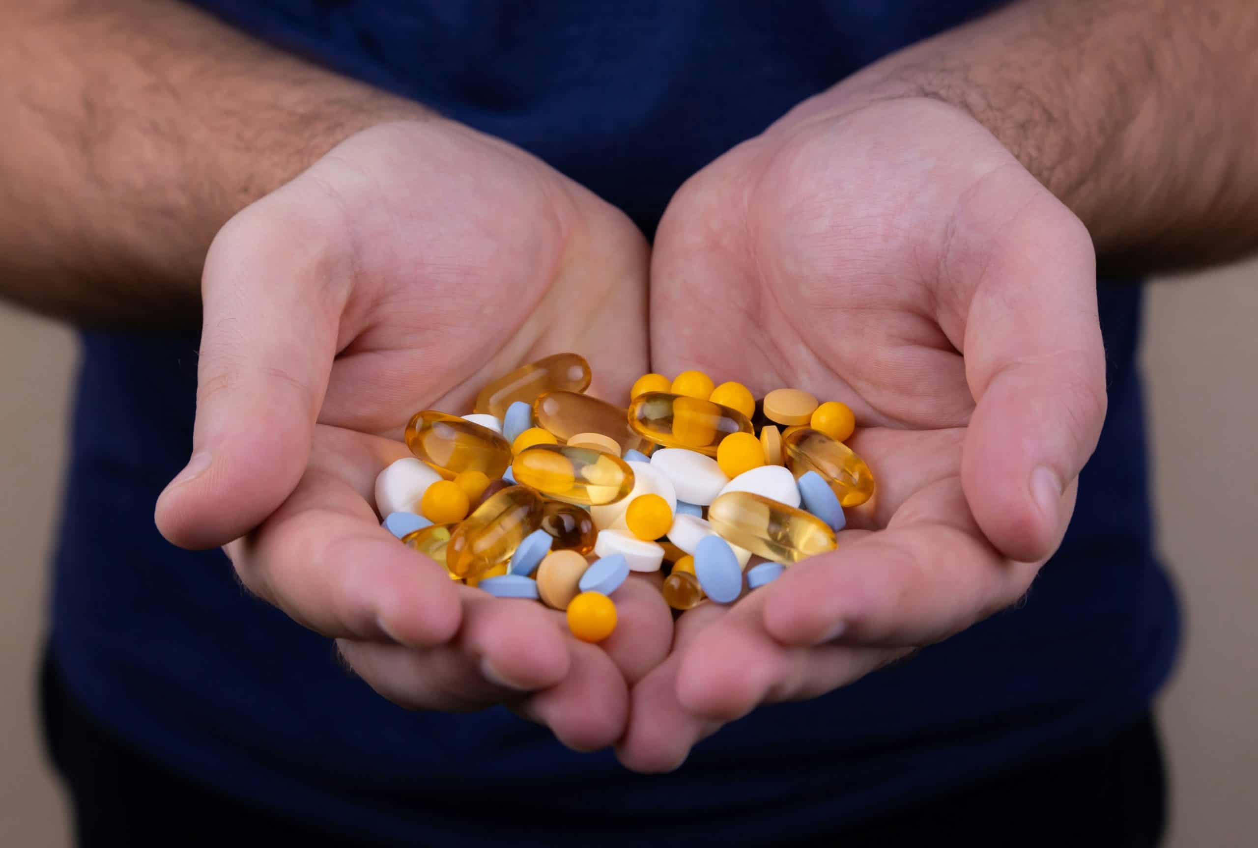 A person holding a handful of pills / vitamin patch