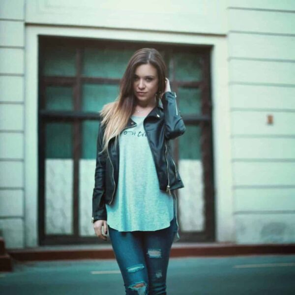 This photo features a woman in a city scene. The blue jeans she wears are part of her street style ensemble.