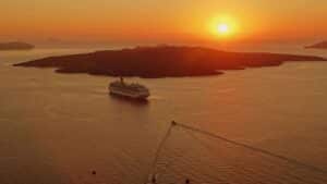 Solo travelers, solo travel, cruise line, cruise ship. A breathtaking sunset view of a cruise ship near the island of Santorini, Greece.