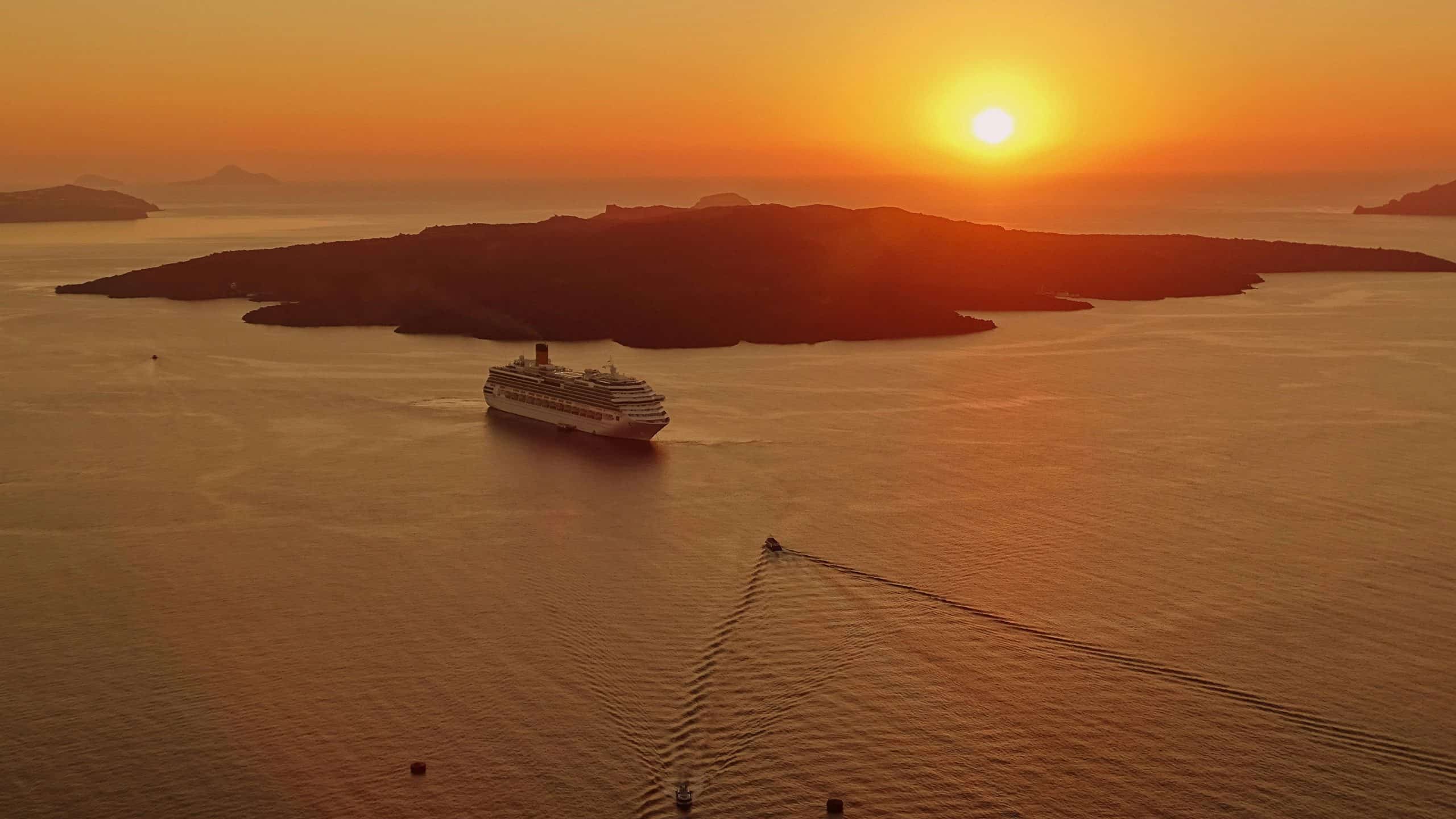 Solo travelers, solo travel, cruise line, cruise ship. A breathtaking sunset view of a cruise ship near the island of Santorini, Greece.