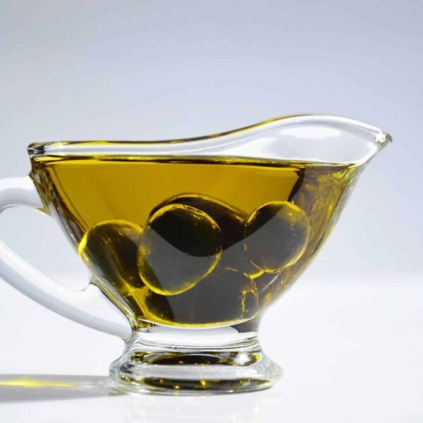 High-resolution image of a glass cup filled with olive oil and olives, ideal for culinary themes.