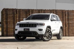 Jeep 4xe, recall, A sleek white Jeep Grand Cherokee parked in front of stacked wooden pallets, showcasing its luxury features.