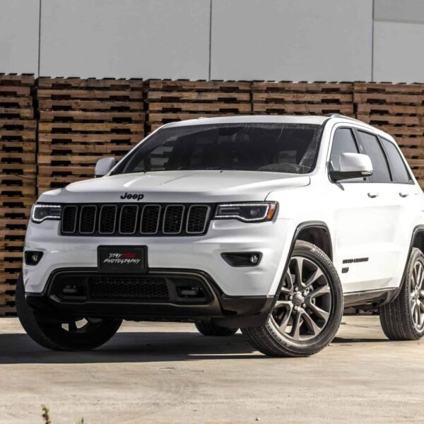 Jeep 4xe, recall, A sleek white Jeep Grand Cherokee parked in front of stacked wooden pallets, showcasing its luxury features.