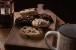 Delicious assorted cookies on a wooden board accompanied by coffee, perfect for a cozy snack time.