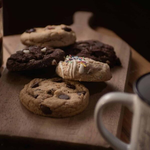 Delicious assorted cookies on a wooden board accompanied by coffee, perfect for a cozy snack time.