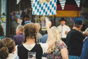 A lively crowd enjoys Oktoberfest outdoors with beer mugs raised. Perfect for festival season visuals.