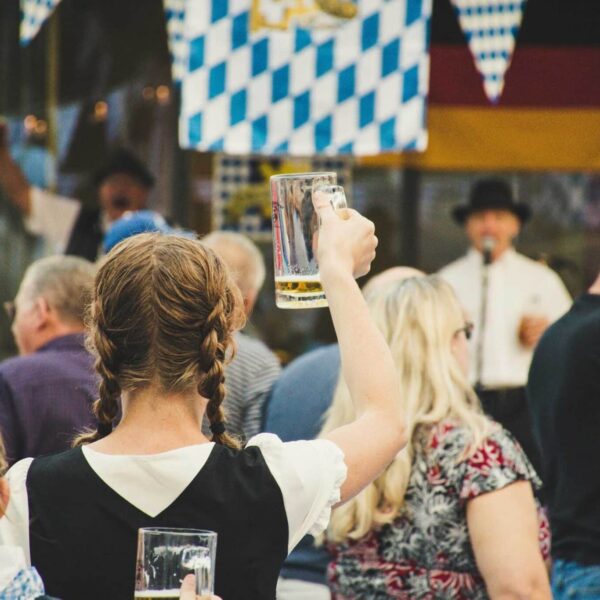 A lively crowd enjoys Oktoberfest outdoors with beer mugs raised. Perfect for festival season visuals.