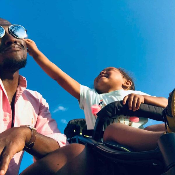 Happy father and daughter bonding moment outdoors under a clear blue sky. Gentle parenting