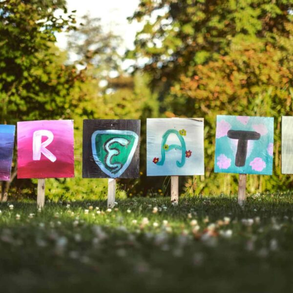 Vibrant painted signs spelling 'CREATE' in a lush outdoor garden setting. creative genius venus in leo