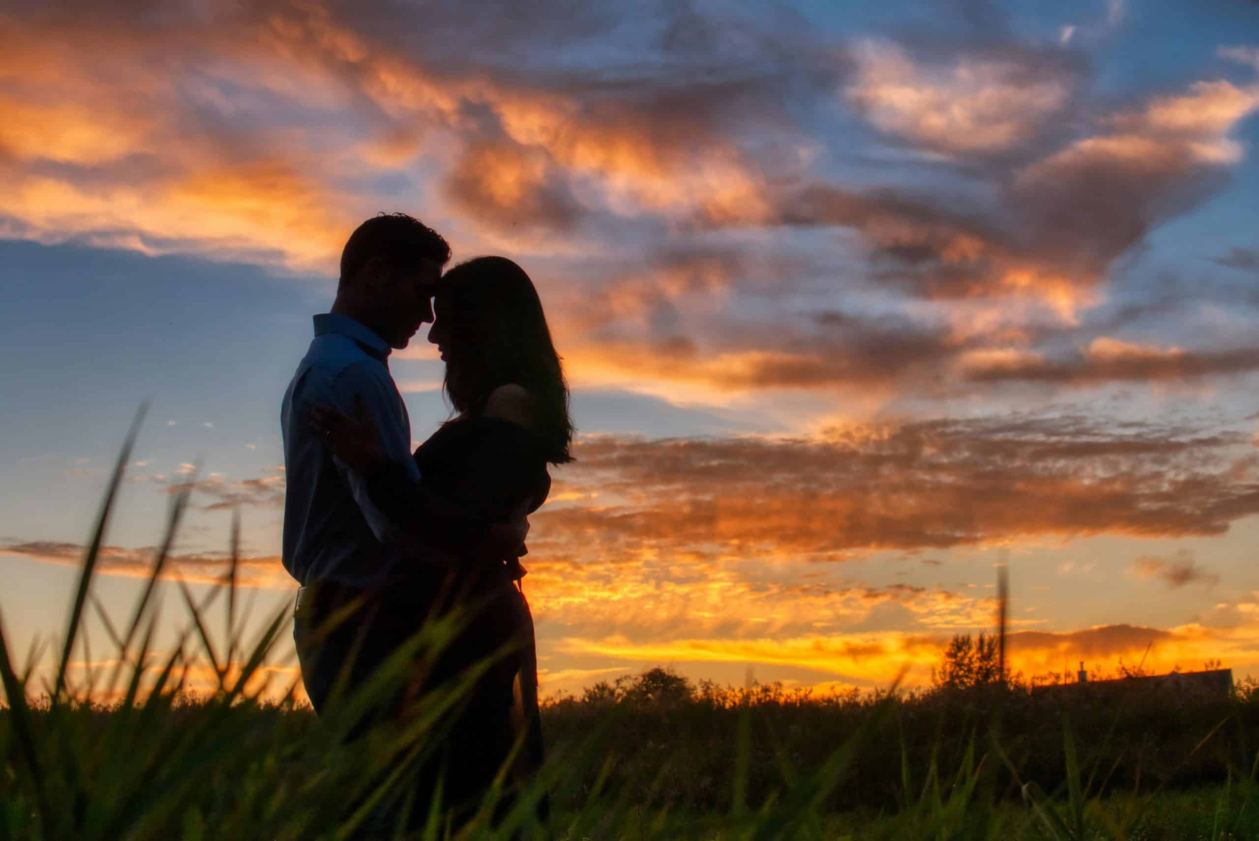 Silhouette of a couple embracing against a vibrant sunset sky, capturing romantic and serene moments.