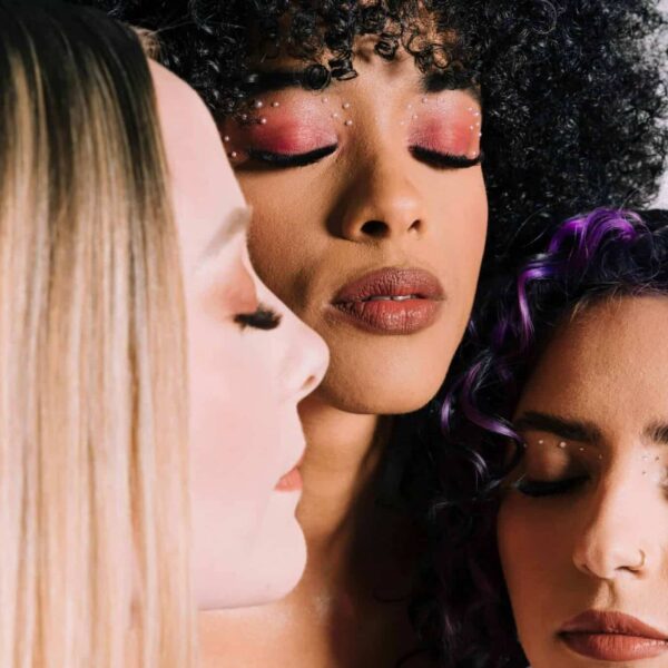 long eyelashes, casual relationships, three women with artistic makeup and closed eyes, showcasing fashion beauty.