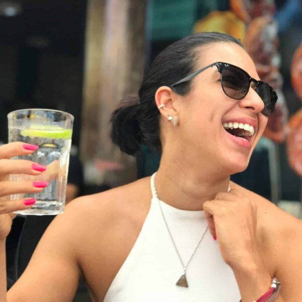 A cheerful woman wearing sunglasses and holding a refreshing drink while enjoying a sunny day, Hydrated, Heat Exposure