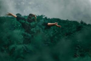 A woman with open arms enjoying freedom in a foggy green landscape. nature