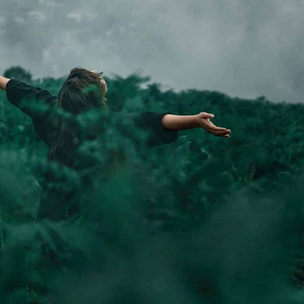 A woman with open arms enjoying freedom in a foggy green landscape. nature