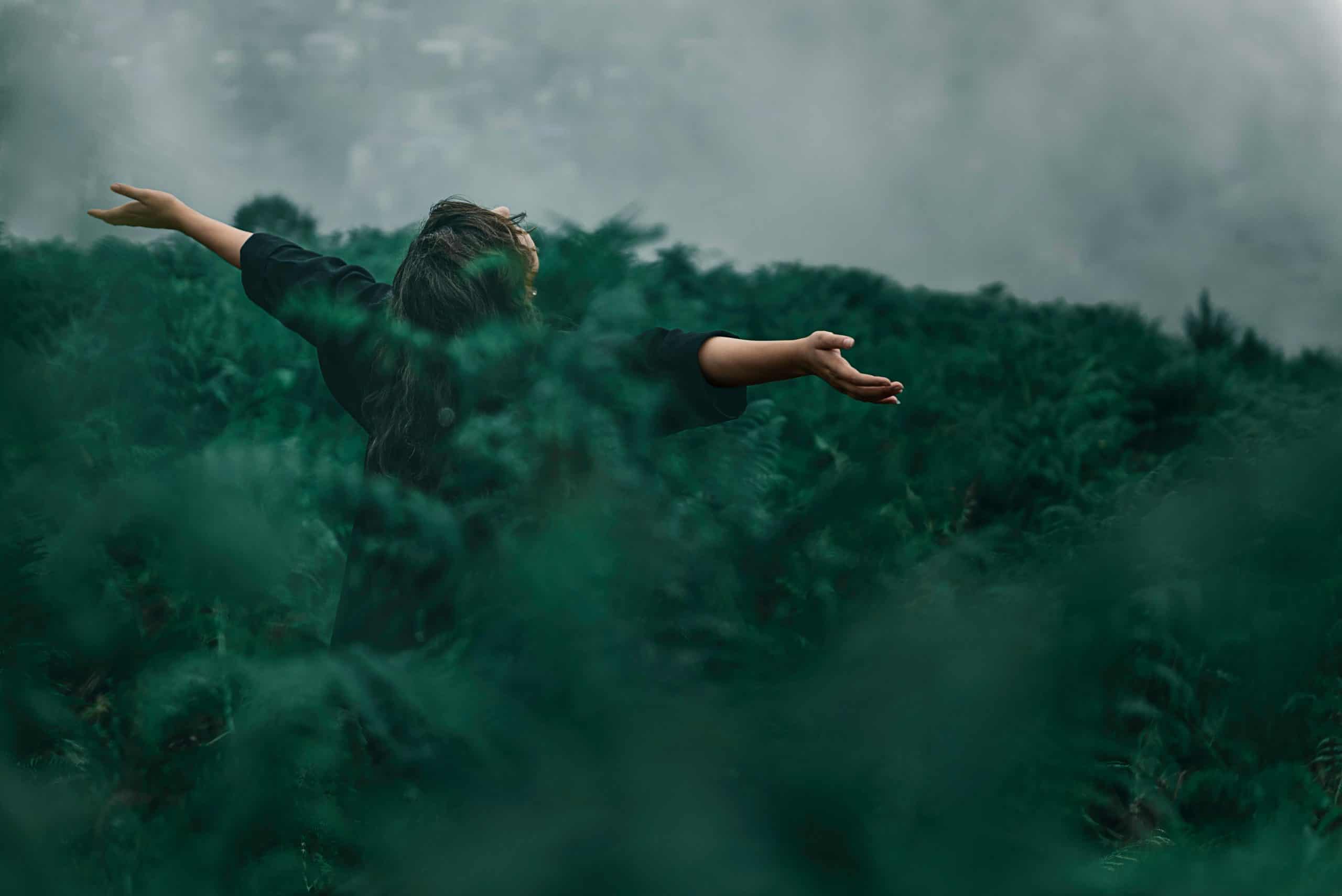 A woman with open arms enjoying freedom in a foggy green landscape. nature