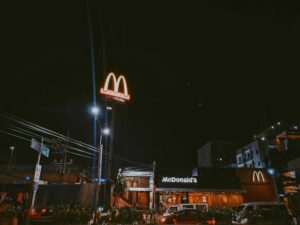 A brightly lit McDonald's restaurant in a city setting during nighttime, showcasing neon signage.