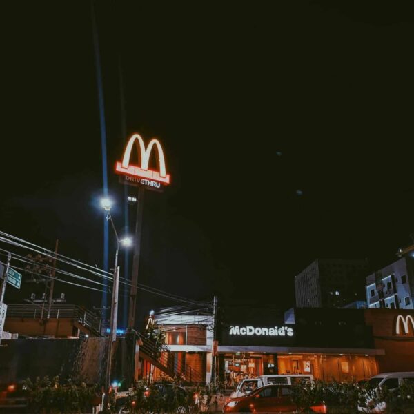 A brightly lit McDonald's restaurant in a city setting during nighttime, showcasing neon signage.