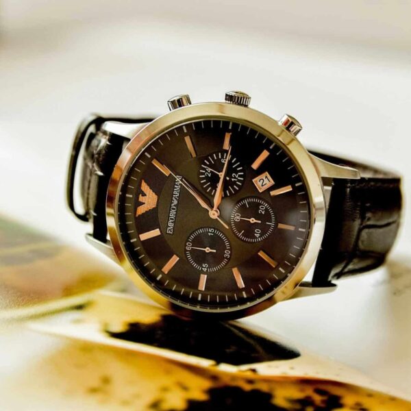 Armani, style lessons, Close-up of a stylish Emporio Armani watch resting on an open book, showcasing luxury and elegance.