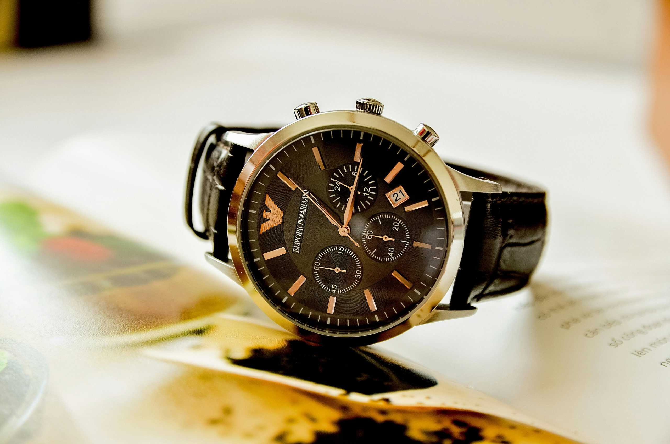 Armani, style lessons, Close-up of a stylish Emporio Armani watch resting on an open book, showcasing luxury and elegance.