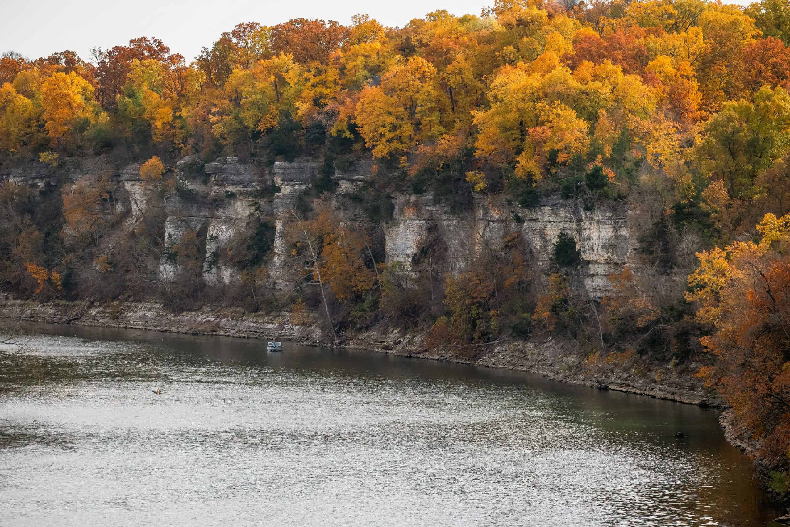 Scenic view of autumnal cliffs and river in Miami, Oklahoma, with vibrant fall foliage.