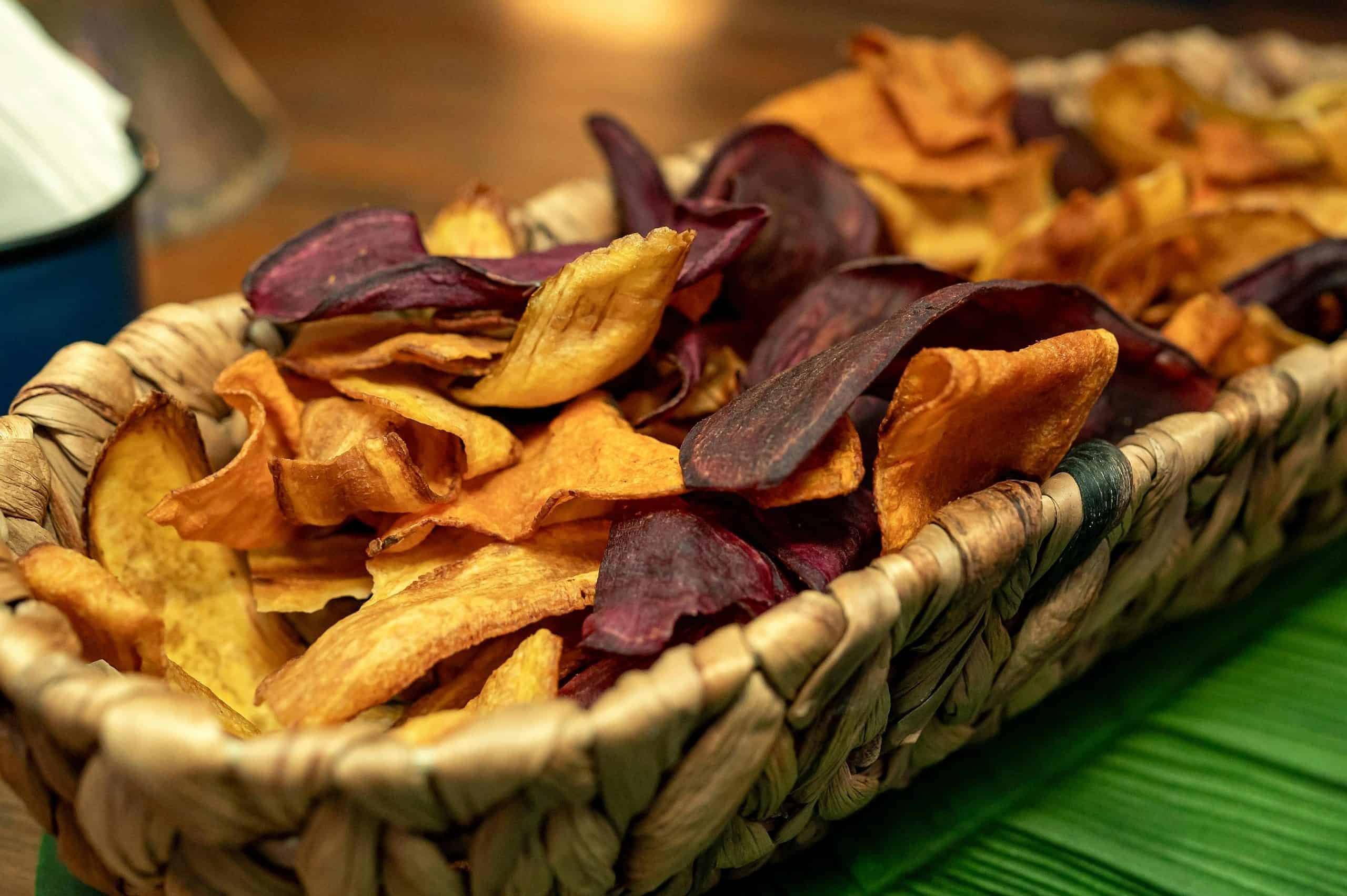 Close-up of a woven basket holding colorful dried vegetable chips.