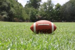 game day food, drinks, A close-up of an American football on a grassy field, highlighting outdoor sports in summer.