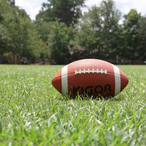 game day food, drinks, A close-up of an American football on a grassy field, highlighting outdoor sports in summer.