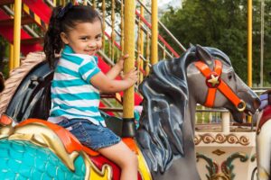 Joyful child enjoying a carousel ride in a vibrant amusement park setting. Theme parks