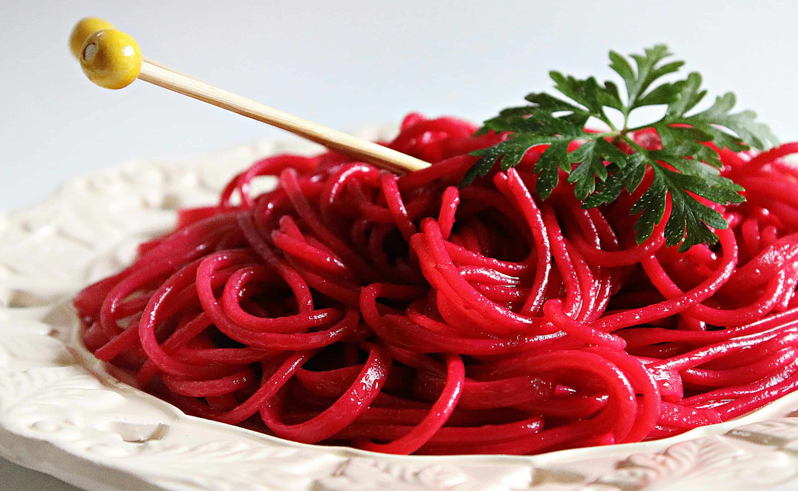 homemade noodles, pasta, red wine, A close-up of vibrant beetroot pasta garnished with fresh parsley on a decorative plate, showcasing colorful and tasty cuisine.